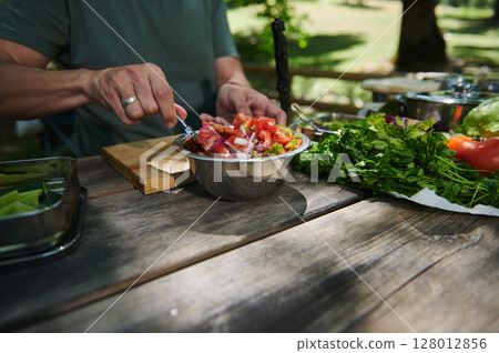Preparing a Fresh Salad with Natural Ingredients on a Wooden Outdoor Table Preparing a Fresh Salad with Natural Ingredients on a Wooden Outdoor Table 128012856