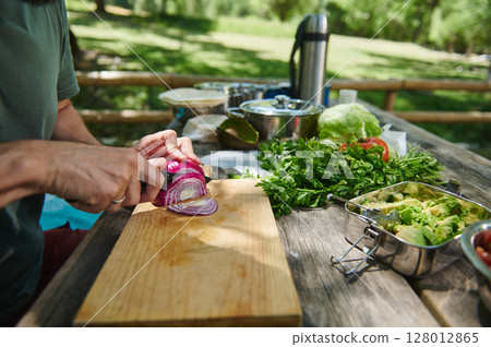 Person Preparing Vegetables on Wooden Cutting Board Outdoors for a Picnic Meal Person Preparing Vegetables on Wooden Cutting Board Outdoors for a Picnic Meal 128012865