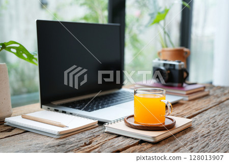 Orange juice and a laptop and notebook, cozy workspace by the window 128013907