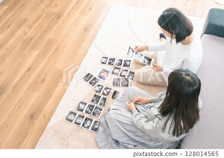 母親和女兒正在查看超音波影像,熱切地等待寶寶的出生 母親和女兒正在查看超音波影像,熱切地等待寶寶的出生 128014565