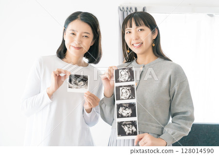 Mother and daughter looking at ultrasound images, eagerly awaiting the birth of their baby Mother and daughter looking at ultrasound images, eagerly awaiting the birth of their baby 128014590