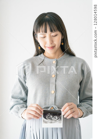 Portrait of a pregnant woman holding an ultrasound photo Portrait of a pregnant woman holding an ultrasound photo 128014598