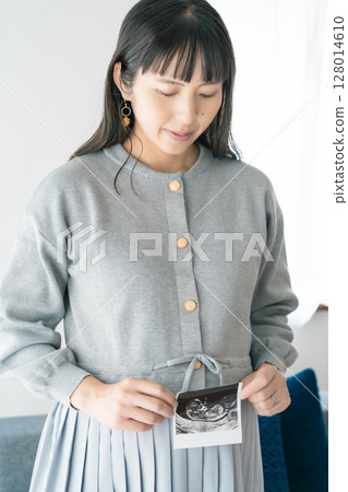 Portrait of a pregnant woman holding an ultrasound photo 128014610