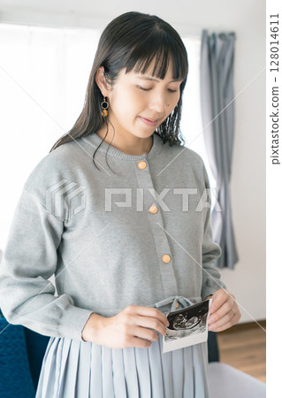 Portrait of a pregnant woman holding an ultrasound photo 128014611