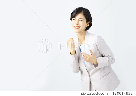 Business woman operating a smartphone in front of a white background 128014935