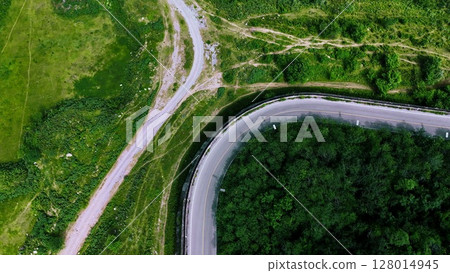 Aerial view of a road in the middle of the forest. Top view of asphalt road through forest with car adventure. Healthy environment road trip travel. Aerial view of a road in the middle of the forest. Top view of asphalt road through forest with car adventure. Healthy environment road trip travel. 128014945