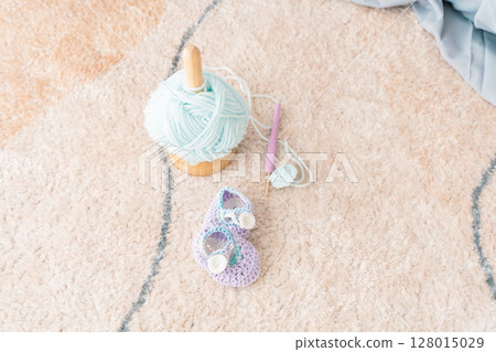 A pregnant woman knitting baby shoes A pregnant woman knitting baby shoes 128015029
