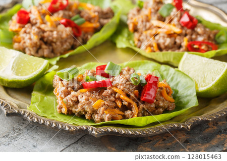 Asian Lettuce Wraps are filled with saucy, gingery beef and vegetables close-up on the plate. Horizontal 128015463