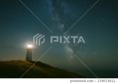 A lighthouse and the heavens lit up on a starry night 128015612