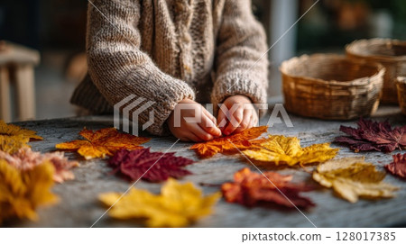 Toddler Arranging Colorful Autumn Leaves on Wooden Table 128017385