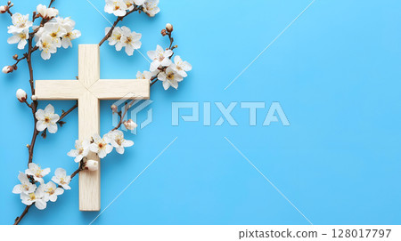 A wooden cross surrounded by delicate blossoms on a vibrant blue background 128017797