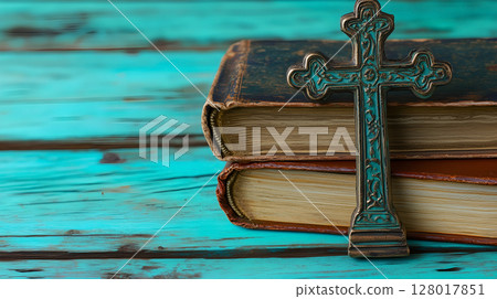 A decorative cross placed on top of vintage books resting on a wooden surface in tranquil setting 128017851