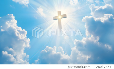 A brilliant cross illuminated by sunlight against a backdrop of clouds in a serene sky 128017865