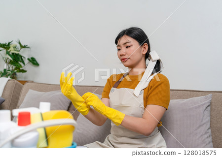 Young modern Asian woman doing house cleaning at home. Confident and independent homemaker maintaining a clean, stylish living space. 128018575