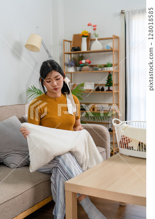 Young modern Asian woman doing house cleaning at home. Confident and independent homemaker maintaining a clean, stylish living space. Young modern Asian woman doing house cleaning at home. Confident and independent homemaker maintaining a clean, stylish living space. 128018585