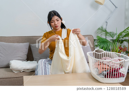 Young modern Asian woman doing house cleaning at home. Confident and independent homemaker maintaining a clean, stylish living space. 128018589