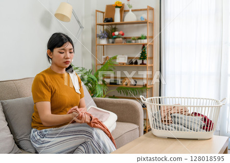 Young modern Asian woman doing house cleaning at home. Confident and independent homemaker maintaining a clean, stylish living space. Young modern Asian woman doing house cleaning at home. Confident and independent homemaker maintaining a clean, stylish living space. 128018595