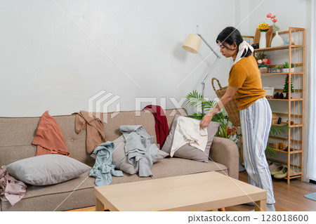 Young modern Asian woman doing house cleaning at home. Confident and independent homemaker maintaining a clean, stylish living space. 128018600