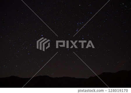 The mountains of Chichibu and the Orion constellation shining in the starry sky in winter 128019170