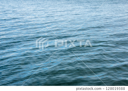 Water background of lake Traunsee in the Alps. The colorful texture of reflections of a clear mountain lake. Texture of water with reflections. 128019388