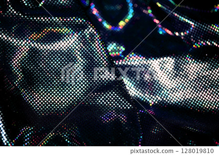 Holographic shiny spots and dots bokeh on fabric for a futuristic disco background Holographic shiny spots and dots bokeh on fabric for a futuristic disco background 128019810