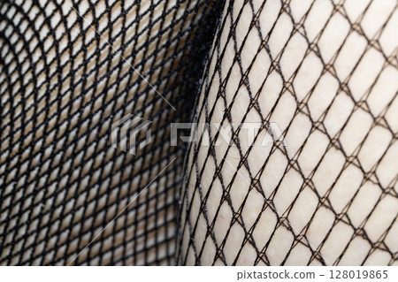 Close up of black fishnet tights on skin legs curves abstract background 128019865