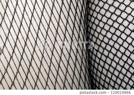 Close up of black fishnet tights on skin legs curves abstract background 128019866