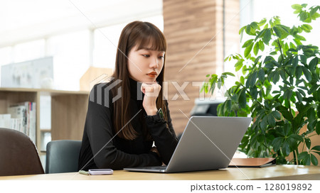 Woman/businesswoman thinking while using a computer Woman/businesswoman thinking while using a computer 128019892