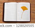 Open Notebook with Pressed Yellow Leaf on Wooden Surface 128020505