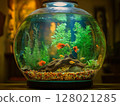 Round home aquarium with small goldfish swimming inside, minimal interior and natural lighting. 128021285