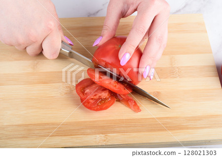 Cutting a tomato into pieces with a knife. Cutting a tomato into pieces with a knife. 128021303
