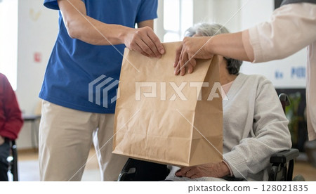 A wheelchair-bound evacuee receives relief supplies at a welfare facility. A wheelchair-bound evacuee receives relief supplies at a welfare facility. 128021835
