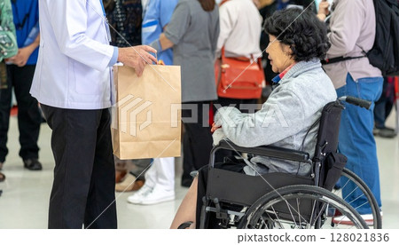 A wheelchair-bound evacuee receives relief supplies at a welfare facility. A wheelchair-bound evacuee receives relief supplies at a welfare facility. 128021836