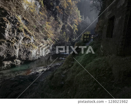 Tranquil mountain stream meanders through rocky gorge in aosta, italy, surrounded by autumn foliage and misty atmosphere under soft sunlight Isollaz waterfall Tranquil mountain stream meanders through rocky gorge in aosta, italy, surrounded by autumn foliage and misty atmosphere under soft sunlight Isollaz waterfall 128021982