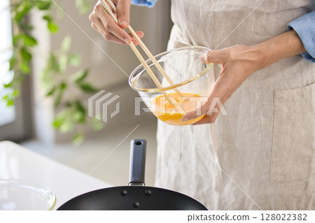 準備雞蛋菜餚的年輕人的手 準備雞蛋菜餚的年輕人的手 128022382