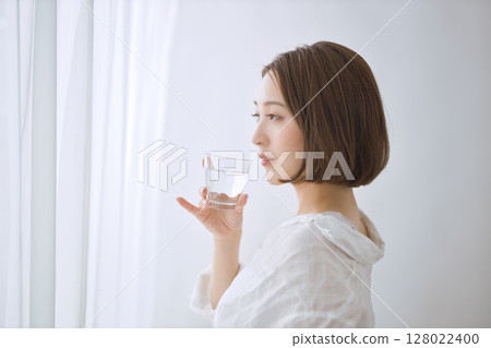 年輕女子在客廳裡喝水 年輕女子在客廳裡喝水 128022400
