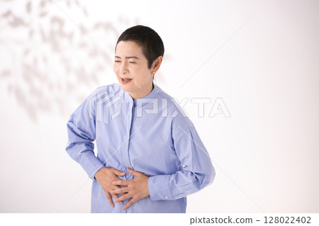 Middle-aged woman grimacing with stomach pain Middle-aged woman grimacing with stomach pain 128022402
