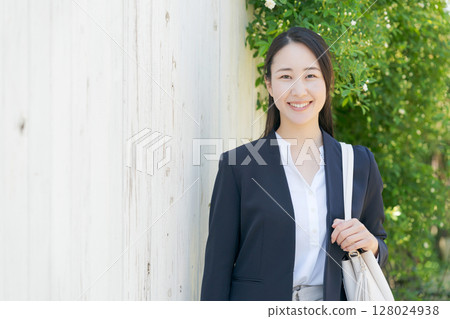 一位身穿西裝的女士站在白色柵欄前 128024938