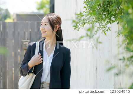 一位身穿西裝的女士站在白色柵欄前 128024940