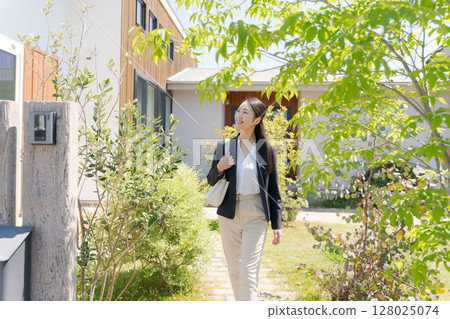 A woman in a suit leaving the front door of her home A woman in a suit leaving the front door of her home 128025074