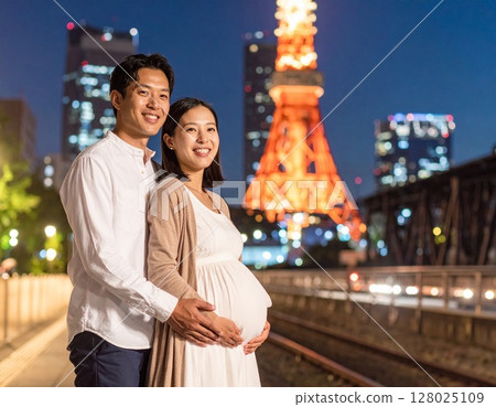 Young Asian pregnant woman and her husband having fun touring Tokyo, Tokyo Tower 128025109