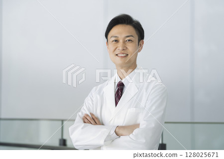 一名 40 多歲的男子身穿白大褂,雙臂交叉,看著鏡頭,醫生/研究人員圖像 一名 40 多歲的男子身穿白大褂,雙臂交叉,看著鏡頭,醫生/研究人員圖像 128025671