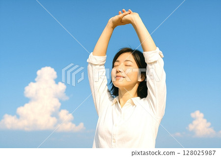 Material with a sense of freedom: cheerful and free. A woman in a white shirt and blue sky. 128025987