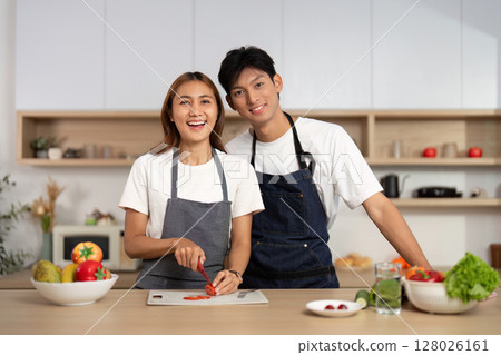 Couple Smiling While Preparing Food in Kitchen. Engaging in healthy cooking together. 128026161