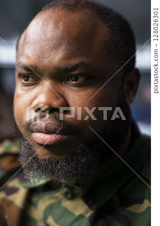 Focus on military operative deploying electronic warfare tools to disrupt enemy communication systems. African american soldier operating on high tech infrastructure, close up 128026301