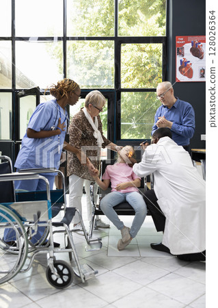 Family emergency unfolds as small girl collapses in hospital lobby with senior grandparents seeking diagnosis and assistance from healthcare professionals during critical pediatric situation. 128026364