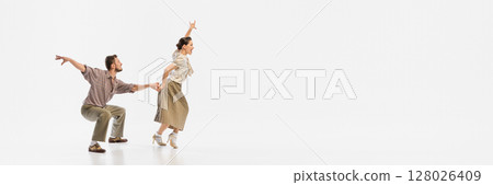 Vintage-styled couple dancing energetically in retro-themed outfits against white background. Banner Vintage-styled couple dancing energetically in retro-themed outfits against white background. Banner 128026409