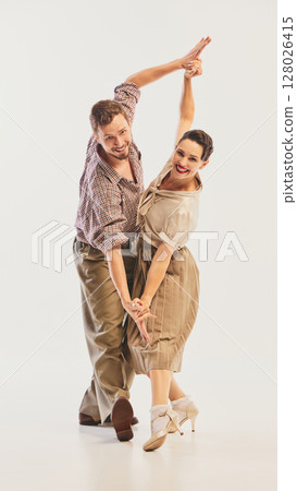 Couple joyfully performing swing dance in vintage attire with energetic and graceful movements Couple joyfully performing swing dance in vintage attire with energetic and graceful movements 128026415