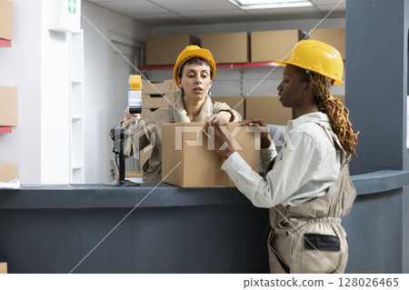 Warehouse activity with diverse employees scanning and registering merchandise, ensuring inventory management and stock control with bar code identification. Import export services. 128026465