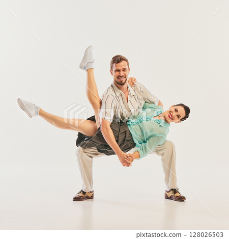 Couple performing dynamic retro dance pose with joyful expressions 128026503